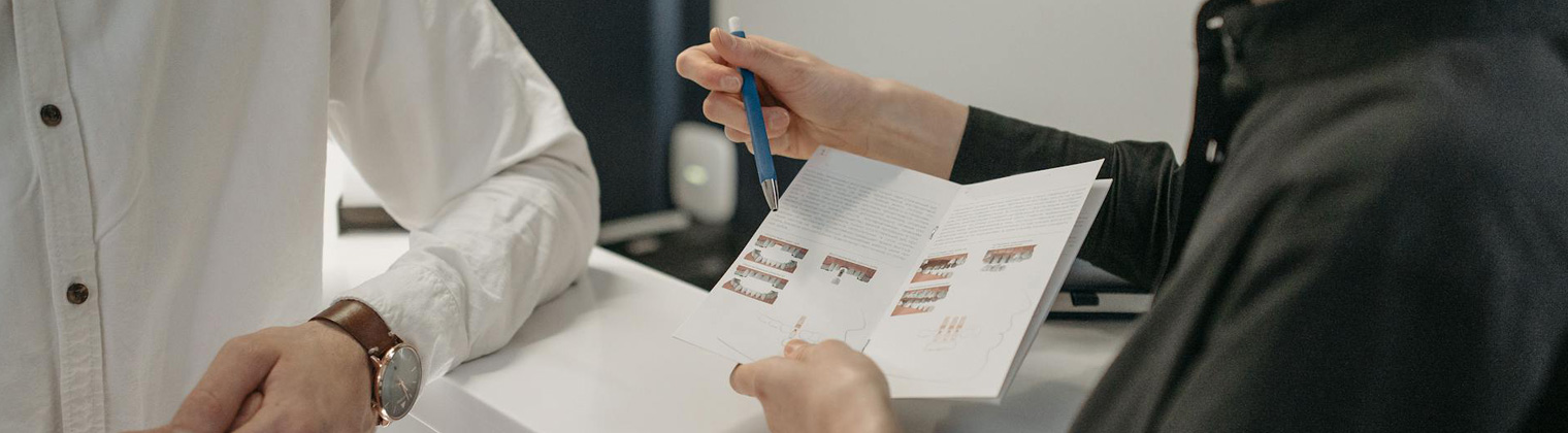 Image of two professionals discussing different brochure designs for their business Image of two professionals discussing different brochure designs for their business